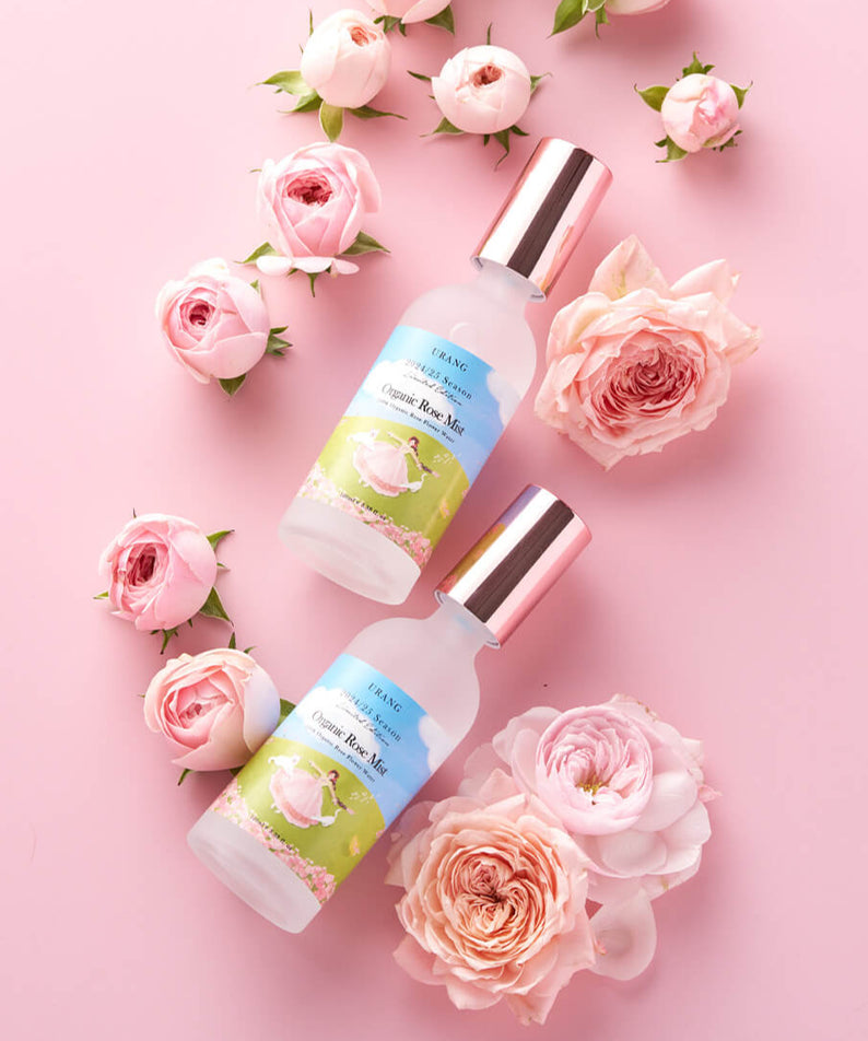 Bouteilles de URANG Organic Rose Mist (2024/2025 Limited Edition) entourées de roses sur fond rose.