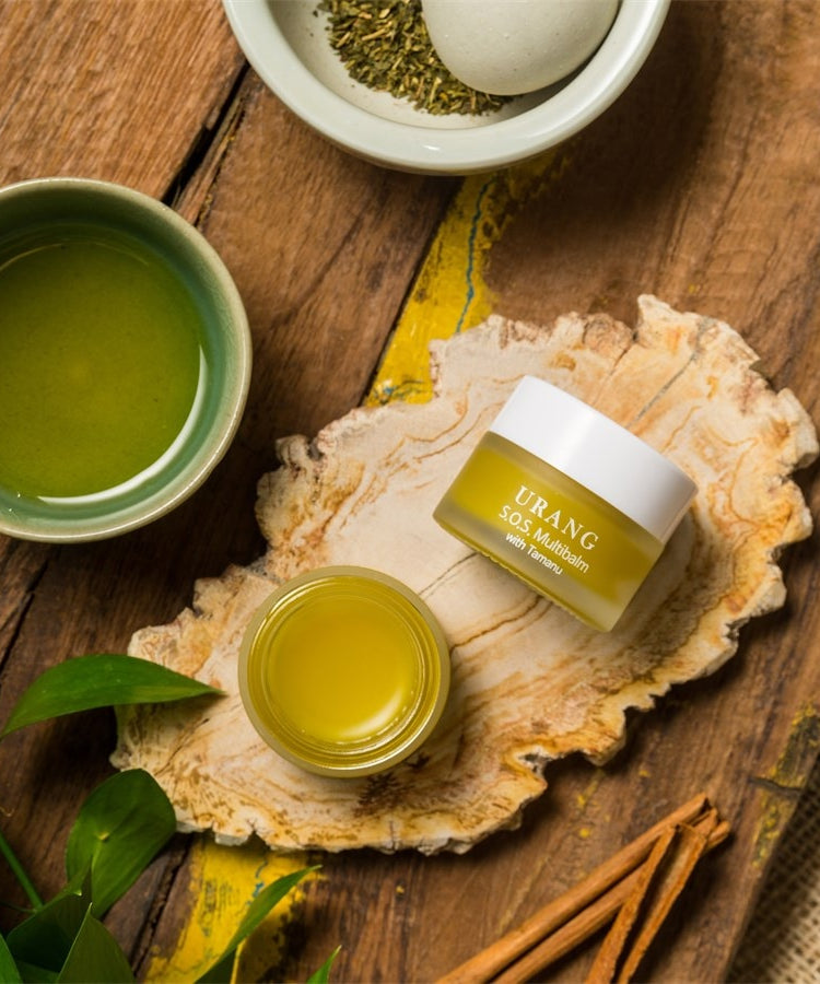 URANG SOS Multi Balm sur un plateau en bois avec des ingrédients naturels, offrant soin apaisant et hydratation en profondeur.