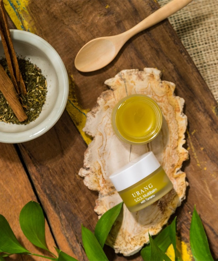 URANG SOS Multi Balm posé sur une table en bois avec décoration naturelle et ingrédients naturels.