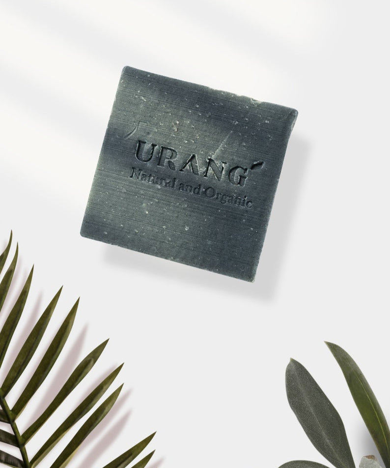 Savon URANG Troubleshooter CP fait main avec inscription, posé sur fond clair, entouré de feuilles, produit naturel et biologique.