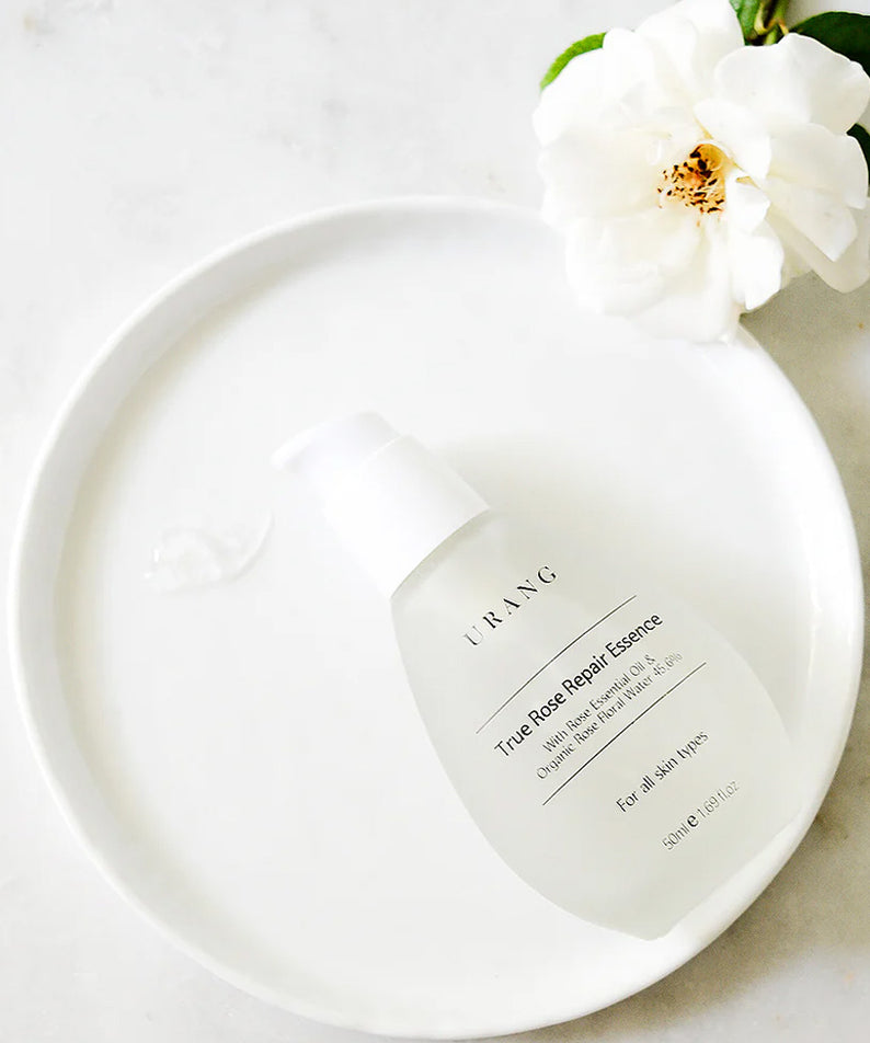 Essence URANG True Rose Repair sur un plateau blanc avec une rose blanche, soin revitalisant pour la peau.