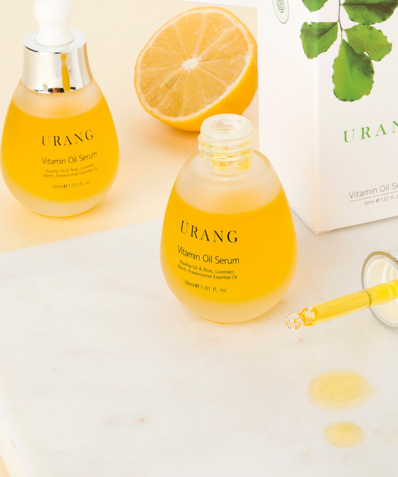URANG Vitamin Oil Serum 30ml sur une table avec un demi-citron en arrière-plan, sérum brillant et élégant en bouteille de 30ml