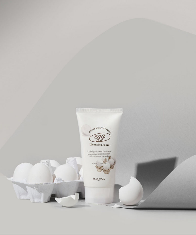 SKINFOOD Egg White Perfect Pore Cleansing Foam 150ml : mousse nettoyante blanche, œufs autour, visuel studio gris clair.