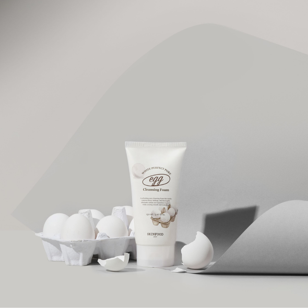 SKINFOOD Egg White Perfect Pore Cleansing Foam 150ml : mousse nettoyante blanche, œufs autour, visuel studio gris clair.