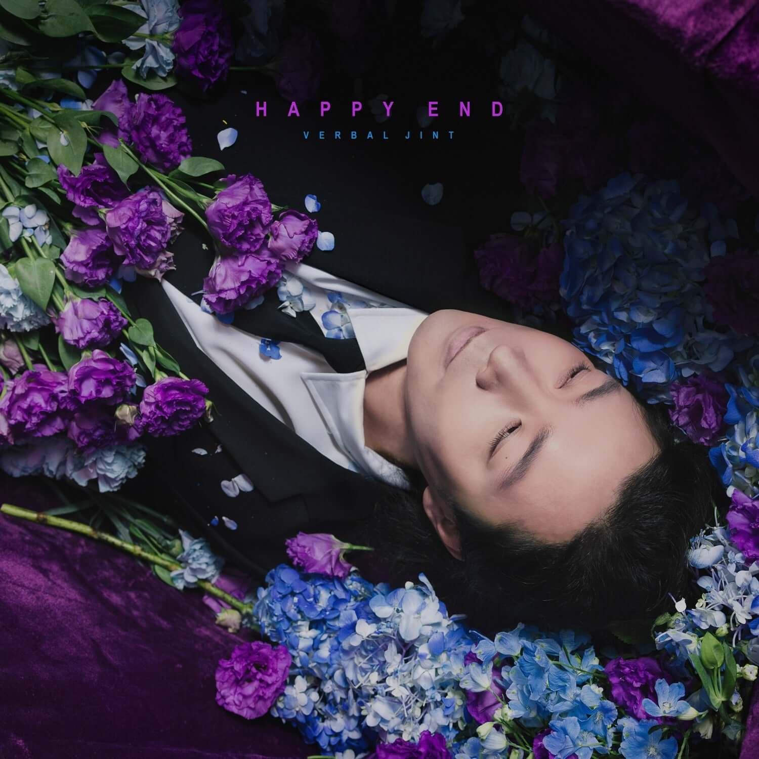 VERBAL JINT - [Happy End] - Album Kpop : couverture avec chanteur allongé entouré d’hortensias violets et bleus, fleurs et ambiances.