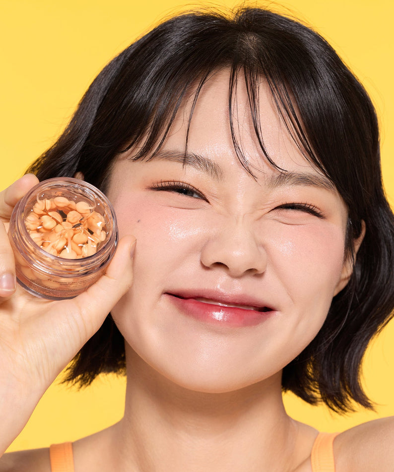 VT COSMETIC Vitamin C Astaxanthin Capsule Cream 50ml, photo beauté sur fond jaune, femme tenant un pot de capsules décoratives.