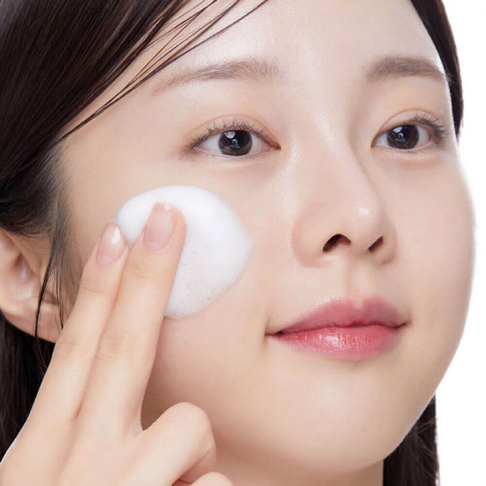 Décris l'image en français : VT COSMETICS Niacinamide Glutathione Yellow Microbubble Serum 70ml, femme applique la crème visage.