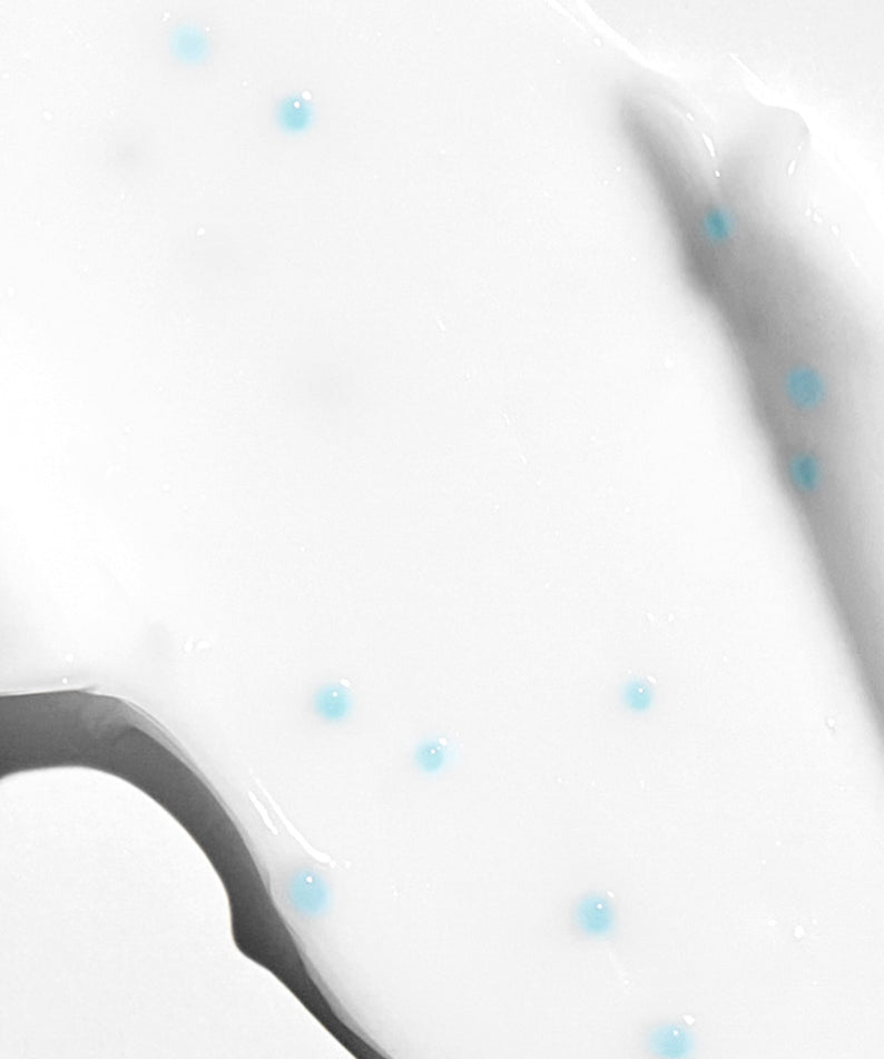 Texture de la VT COSMETIC PDRN Cream 100 50ml avec des micro-bulles bleues sur fond blanc lisse.