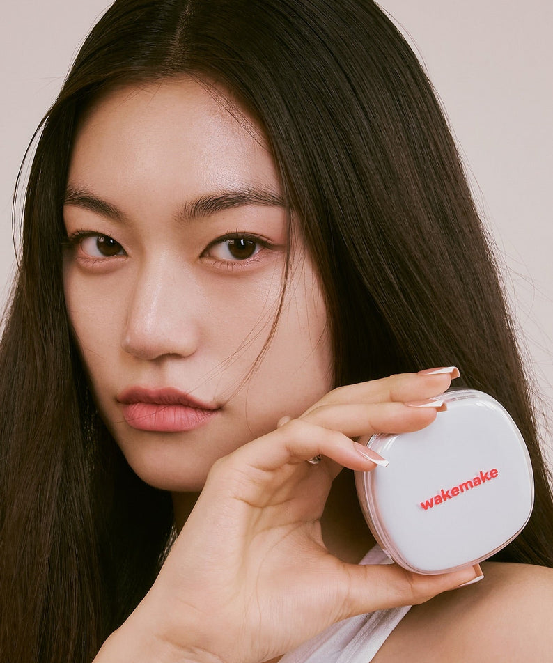 Modèle tenant le WAKE MAKE Seamless Wear Cushion 15g, maquillage innovant pour une peau impeccable.