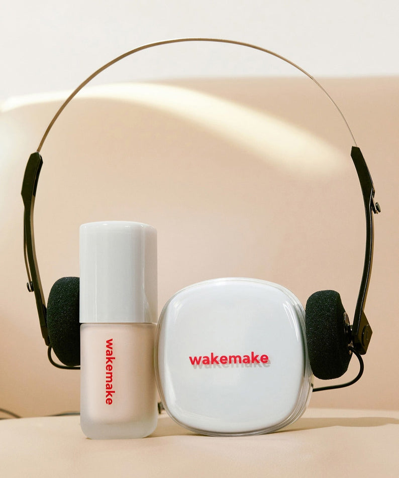 WAKE MAKE Seamless Wear Cushion 15g avec écouteurs sur fond beige élégamment présenté pour un confort et un style moderne.