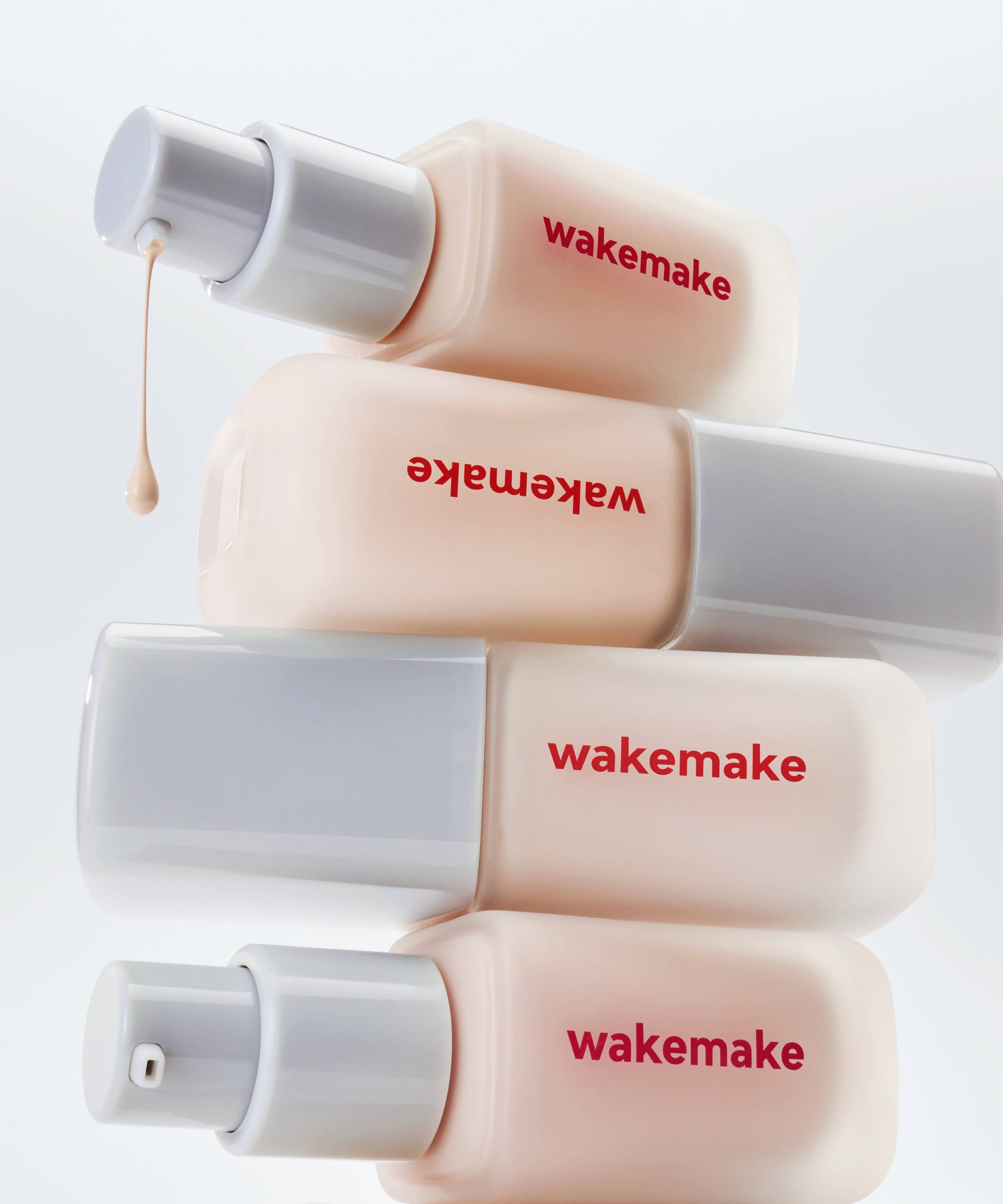 Image de plusieurs flacons WAKE MAKE Seamless Wear Foundation 30ml soigneusement empilés, montrant leur pompe pour application pratique.