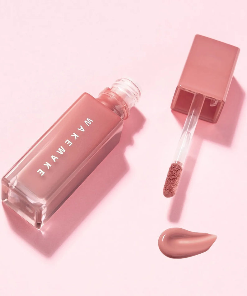Flacon de WAKE MAKE Sheer Glow Liquid Blusher 7g ouvert avec applicateur et blush liquide sur fond rose.