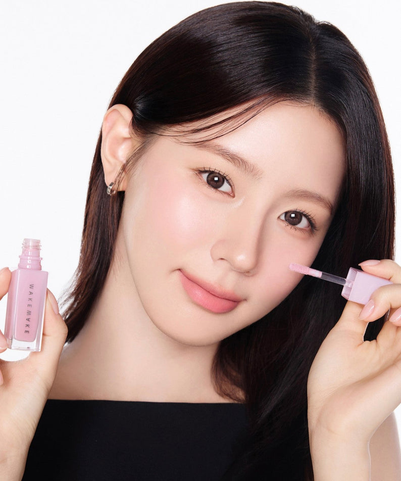 Femme appliquant WAKE MAKE Sheer Glow Liquid Blusher 7g sur ses joues, maquillage lumineux et naturel.