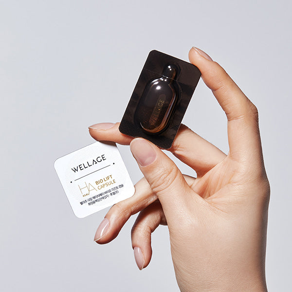 WELLAGE Real Gold Collagen One Day Kit : main tient le flacon et la carte produits, fond clair, marque WELLAGE