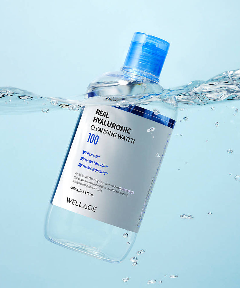 WELLAGE  Real Hyaluronic Cleansing Water 400ml, bouteille en verre bleue avec éclaboussures d’eau, décor salle de bain.