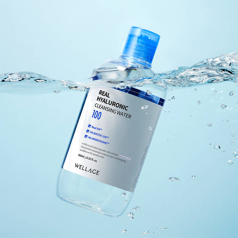WELLAGE  Real Hyaluronic Cleansing Water 400ml, bouteille en verre bleue avec éclaboussures d’eau, décor salle de bain.
