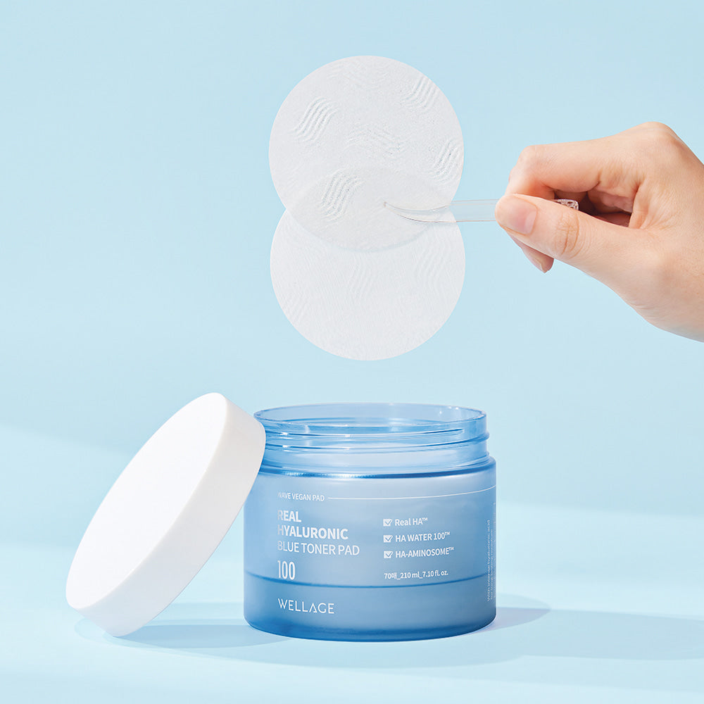 WELLAGE Real hyaluronic Blue Toner Pads 70 Sheets, marque WELLAGE : cotons imbibés bleus sur fond bleu, main tenant