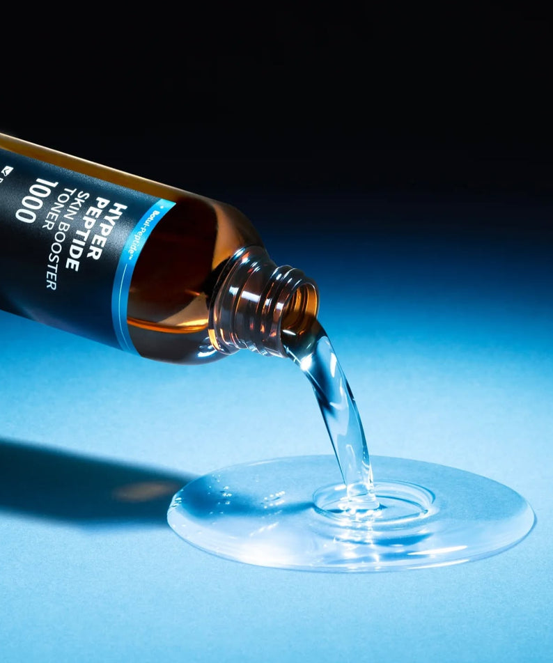 WELLAGE Hyper eptide Skin booster Toner 200ml versé sur une surface bleue, produit soin de la peau révélateur d'éclat.