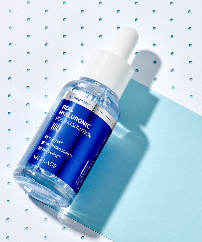 Flacon de WELLAGE Real Hyaluronic Peeling Solution 30ml sur fond géométrique bleu et blanc, produit de soin anti-âge et hydratant.