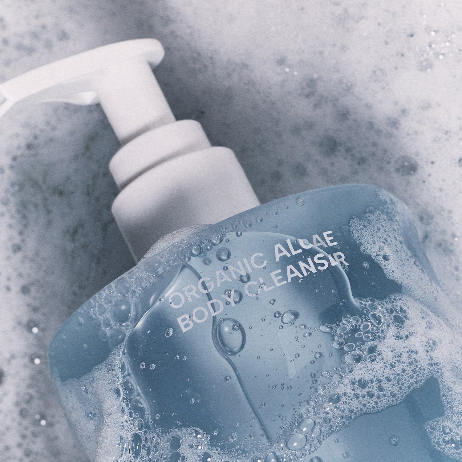 WHAMISA Organic Algae Fermented Body Cleanser 490ml, bouteille WHAMISA dans un bain moussant bleu, contexte visuel produit.