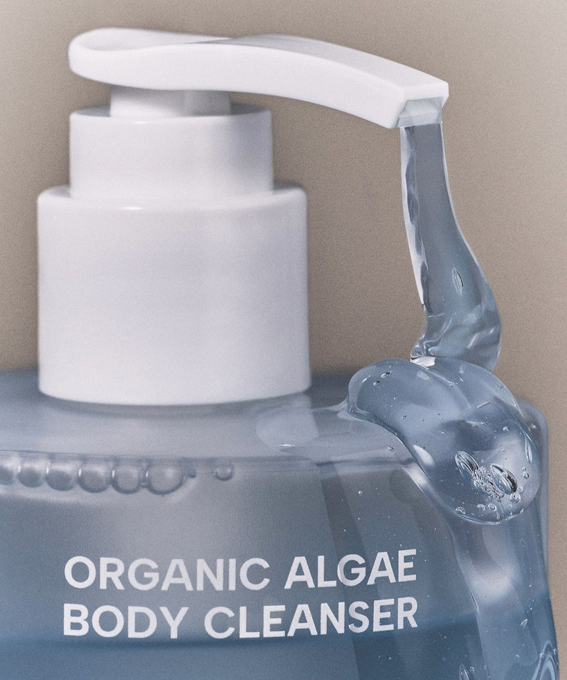WHAMISA Organic Algae Fermented Body Cleanser 490ml en flacon blanc avec pompe, contexte salle de bain, étiquetage algae.