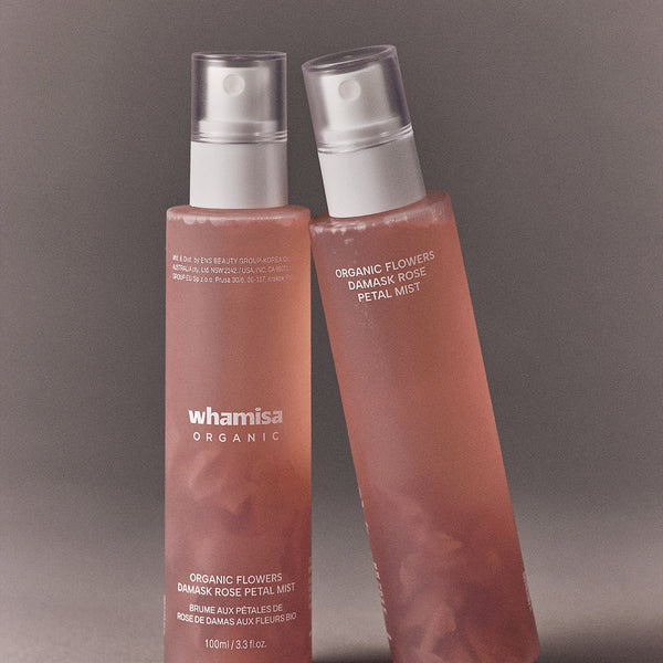Décris l'image en français : WHAMISA Organic Flower Fermented Rose Petal Mist 100ml, deux flacons roses sur fond gris.