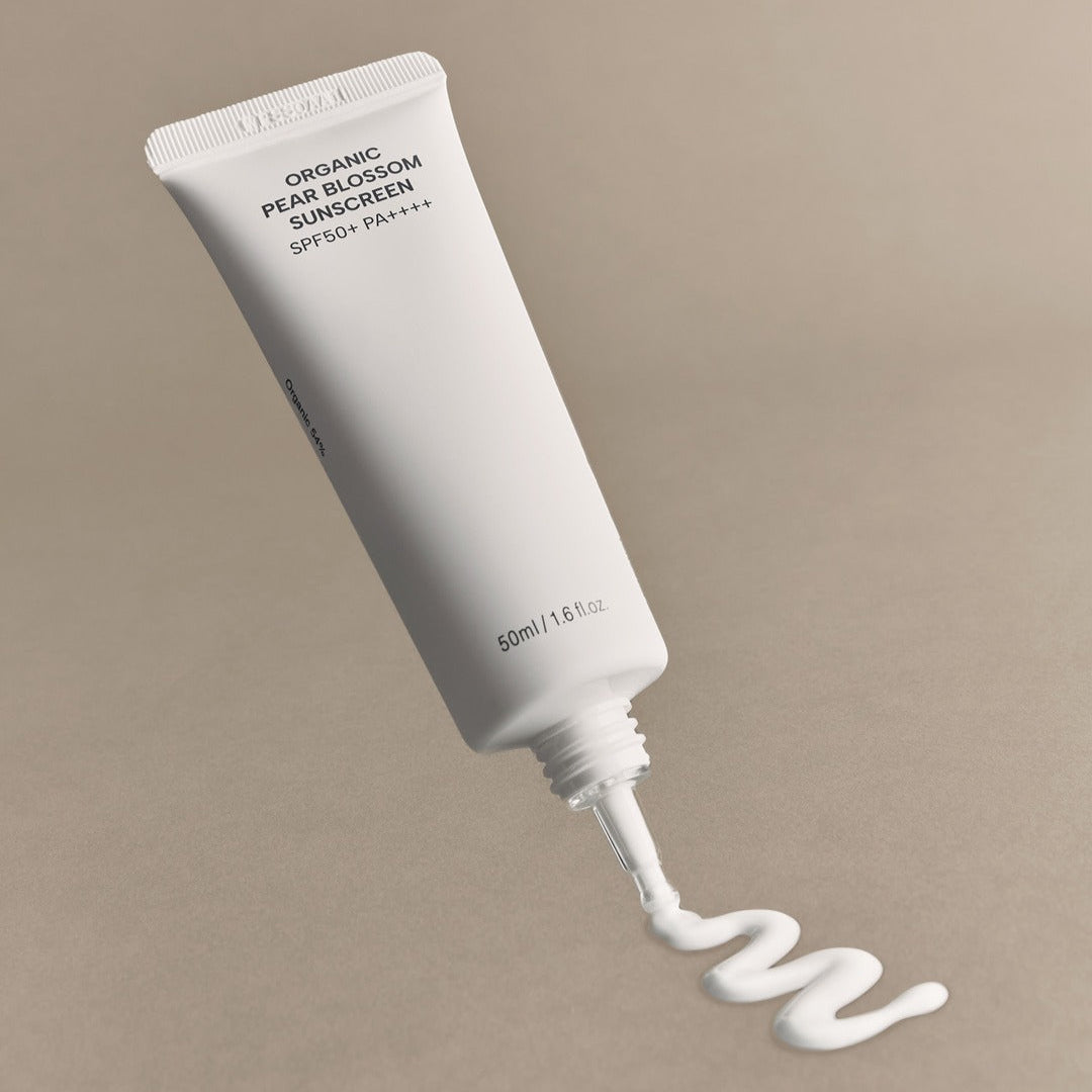 WHAMISA Organic Pear Blossom Fermented Sunscreen 50ml, tube blanc sur fond beige, crème solaire bio en contexte beauté
