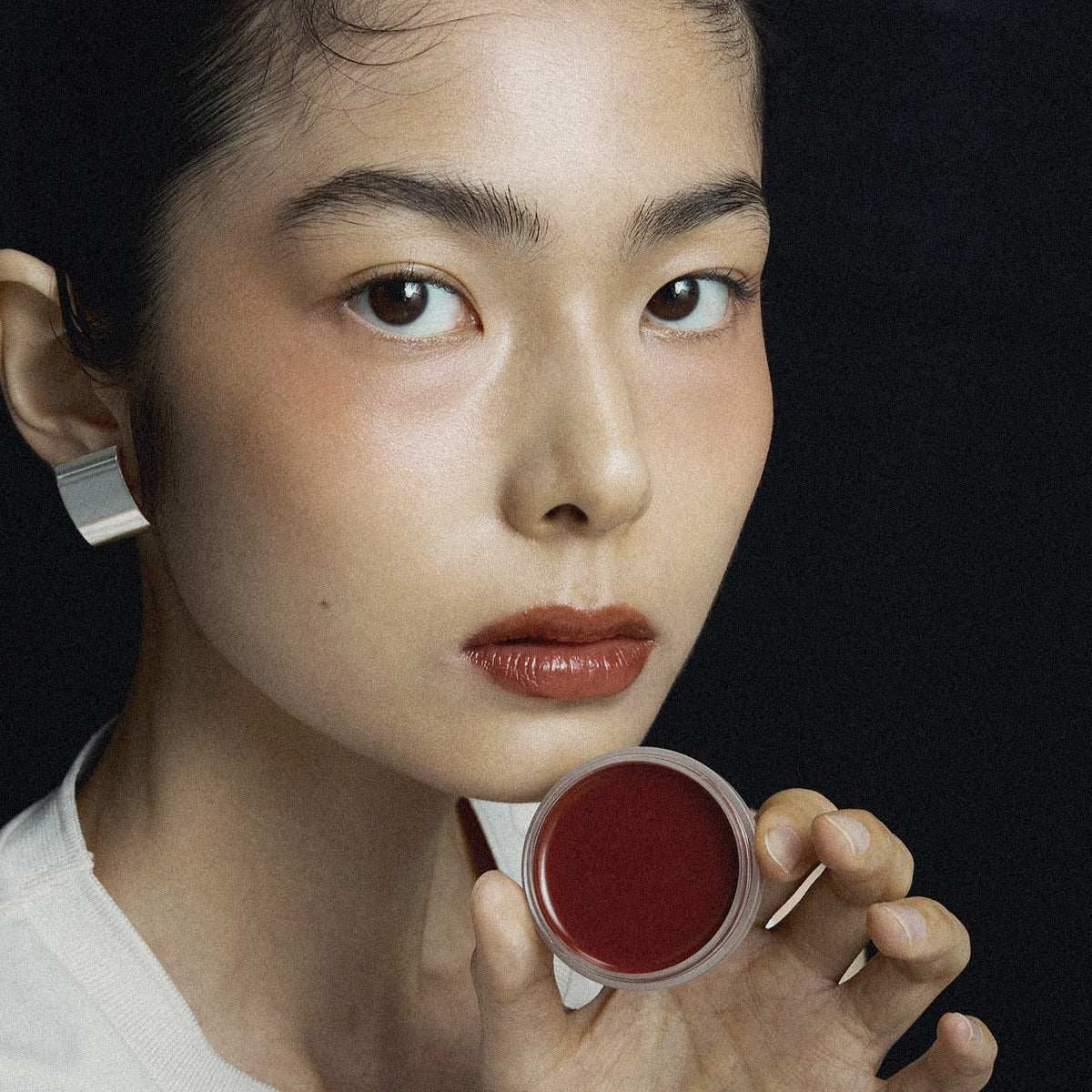 XOUL Ever Moist Volume Lip Balm 8g, femme tenant le baume sur fond sombre, lèvres hydratées, marque XOUL visible.