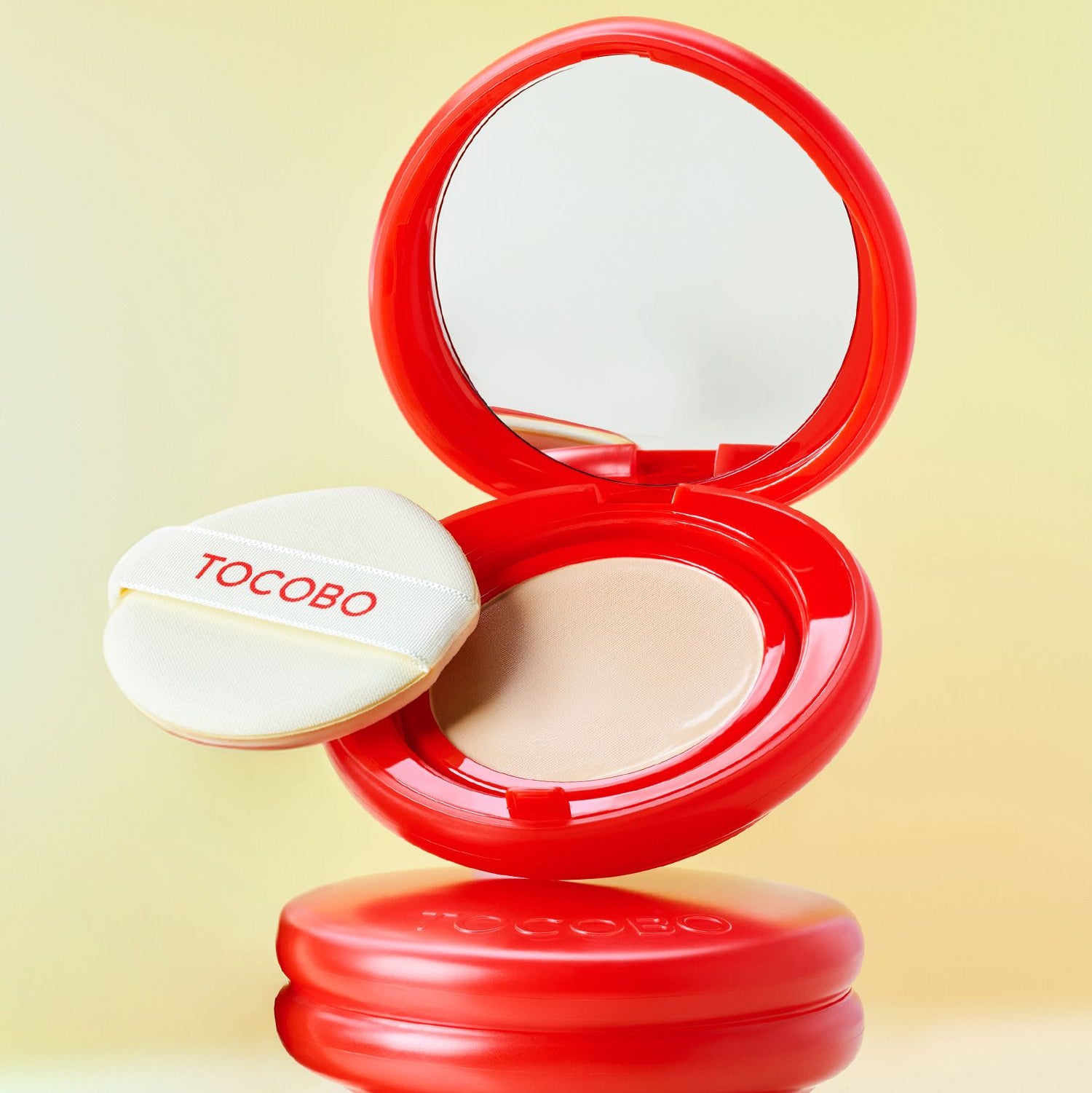 TOCOBO Apple Dewy Fit Cushion de la marque TOCOBO, boîte ouverte rouge sur fond jaune, maquillage teint déwy