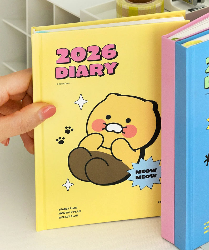 KAKAO FRIENDS Planner 2026, agenda 2026 jaune avec personnages Kakao Friends, sur étagère, mains tenant le carnet.