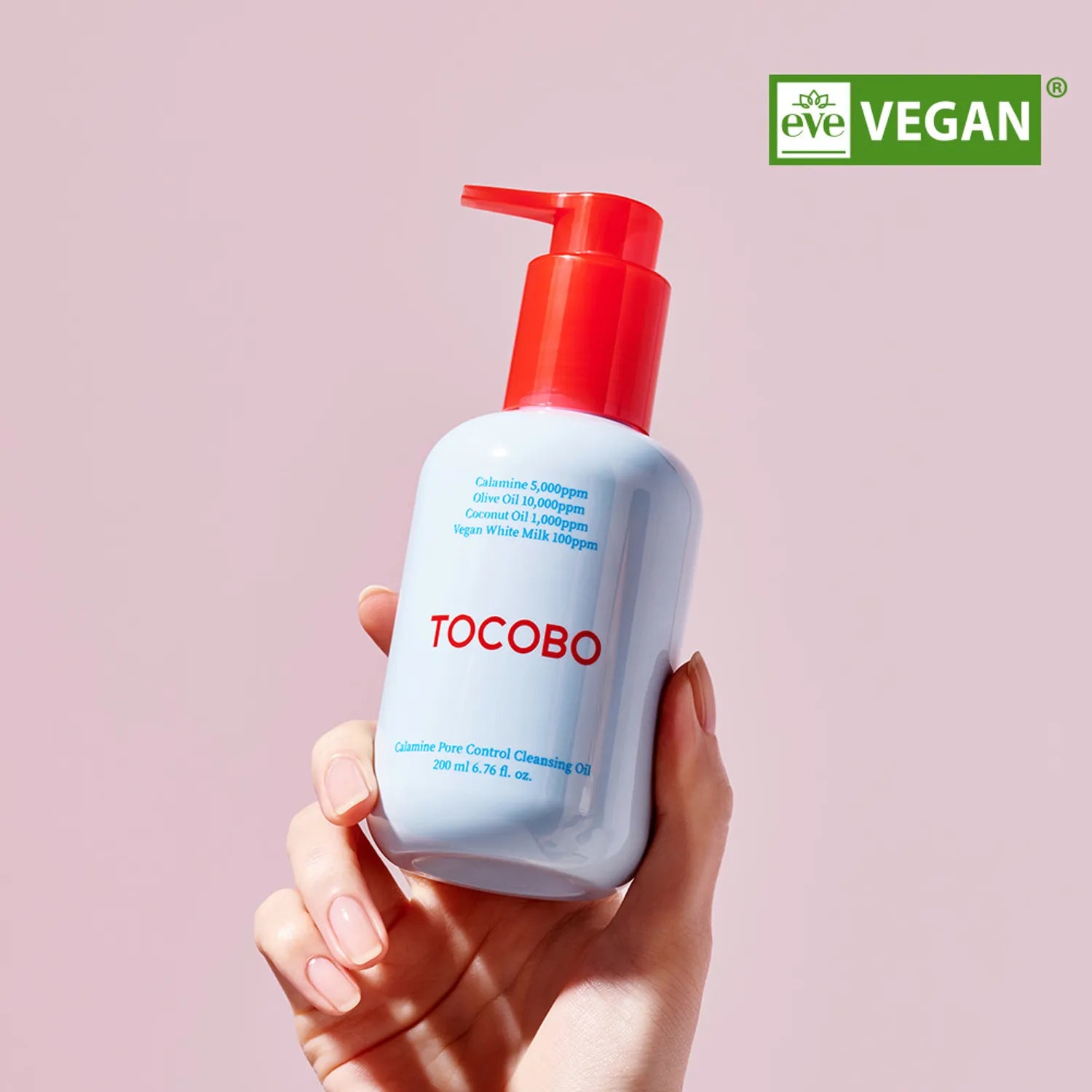 Main tenant TOCOBO Calamine Pore Control Cleansing Oil 200ml, flacon bleu à pompe rouge sur fond rose, vegan