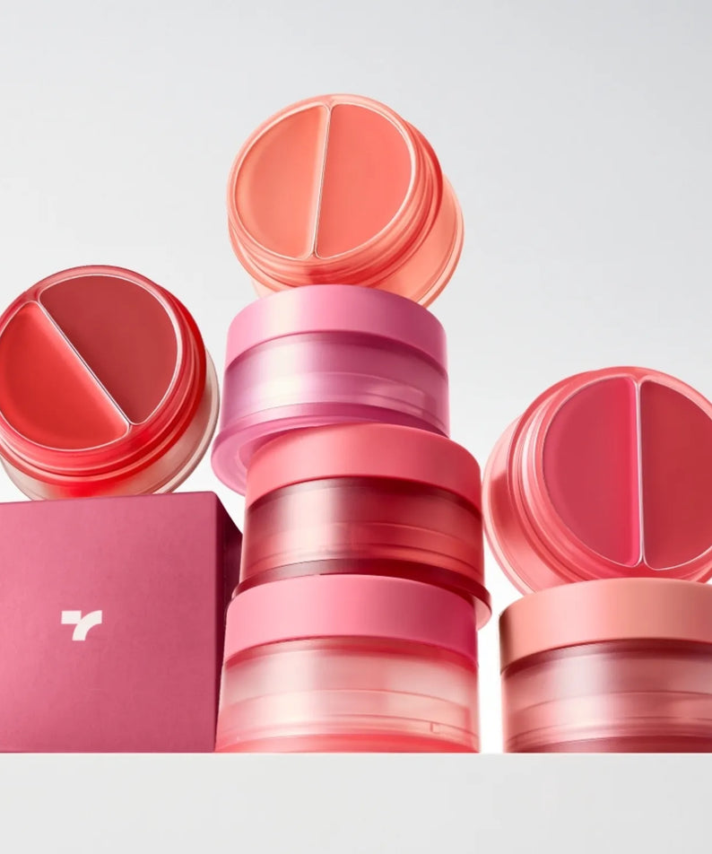 Décris l'image en français : TONY MOLY Cheek Tone Lip & Cheek Duo Balm, baume lèvres et joues, marques et couleurs rose/rouge sur fond clair.