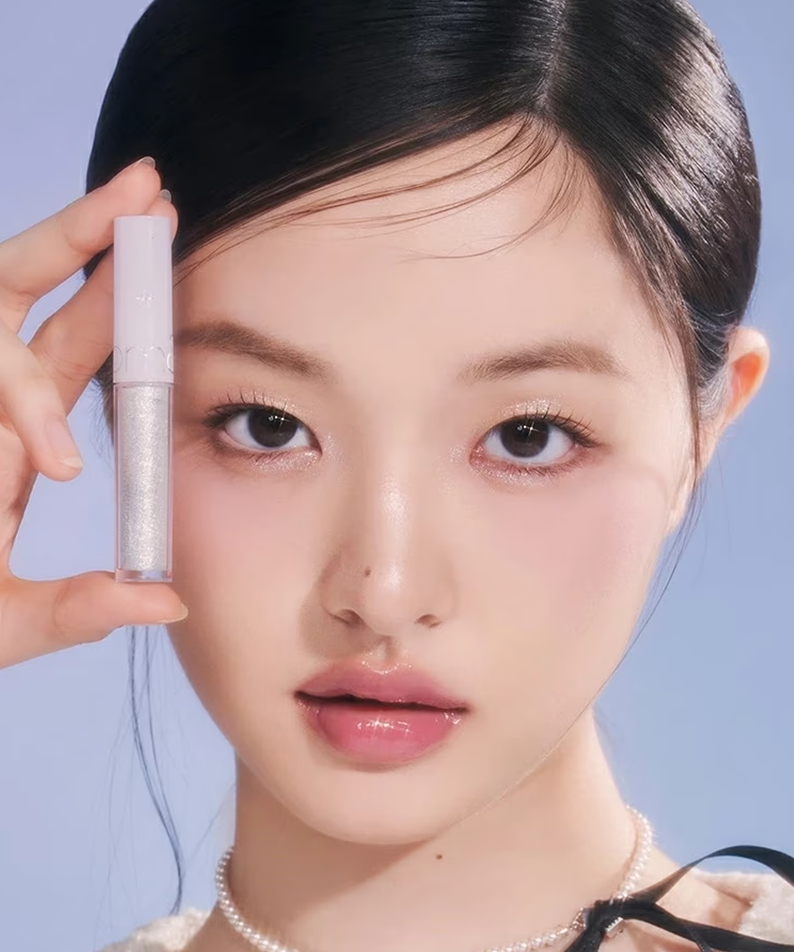 ROMAND The Universe Liquid Glitter par la marque : maquillage pailleté liquide, sur visage, main tenant le produit, fond bleu.