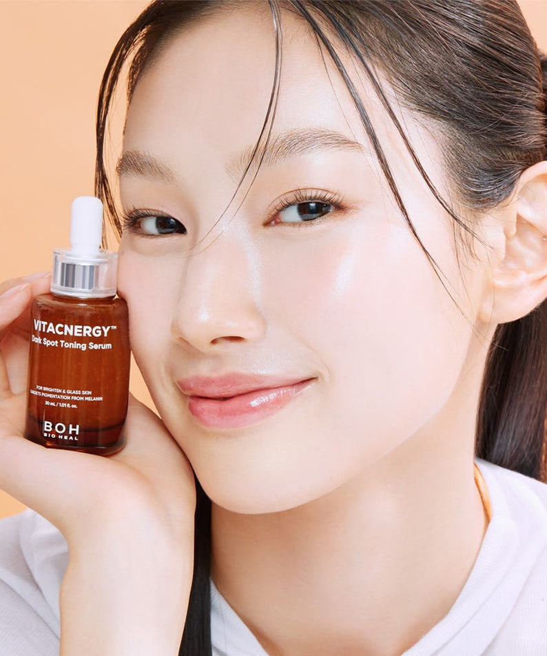 Femme souriante tenant le sérum BIO HEAL BOH Vitacnergy Dark Spot Toning Serum pour éclat de peau et réduction des taches sombres.