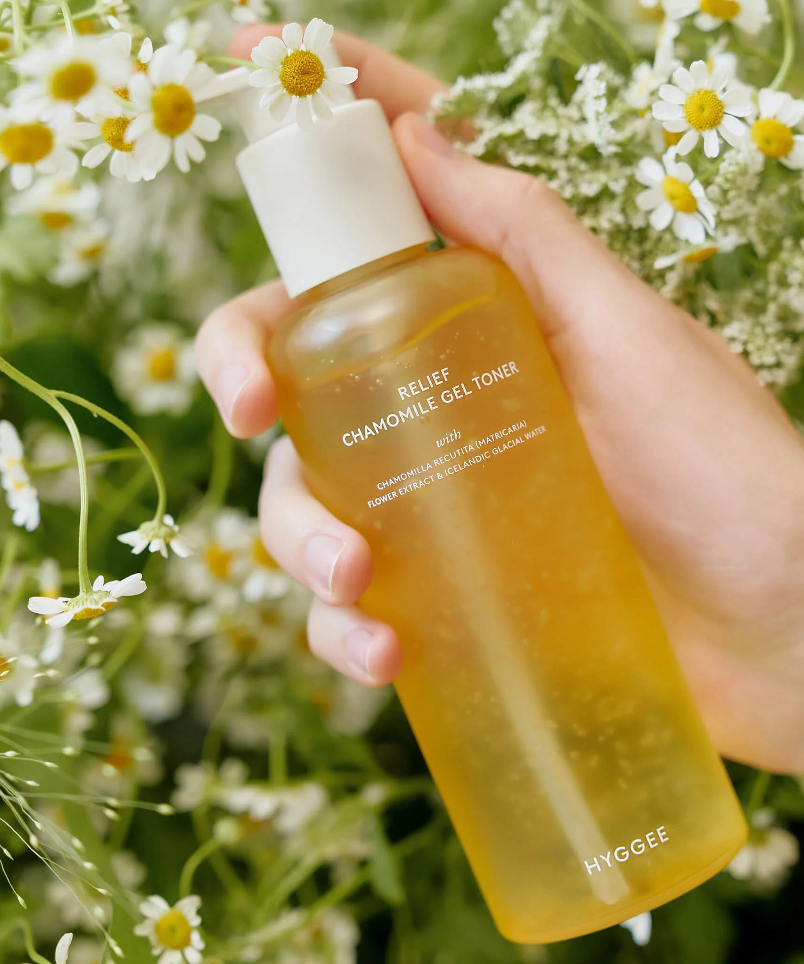 HYGGEE Relief Chamomile Gel Toner 200ml tenue parmi des fleurs de camomille blanches, fond naturel et relaxant.