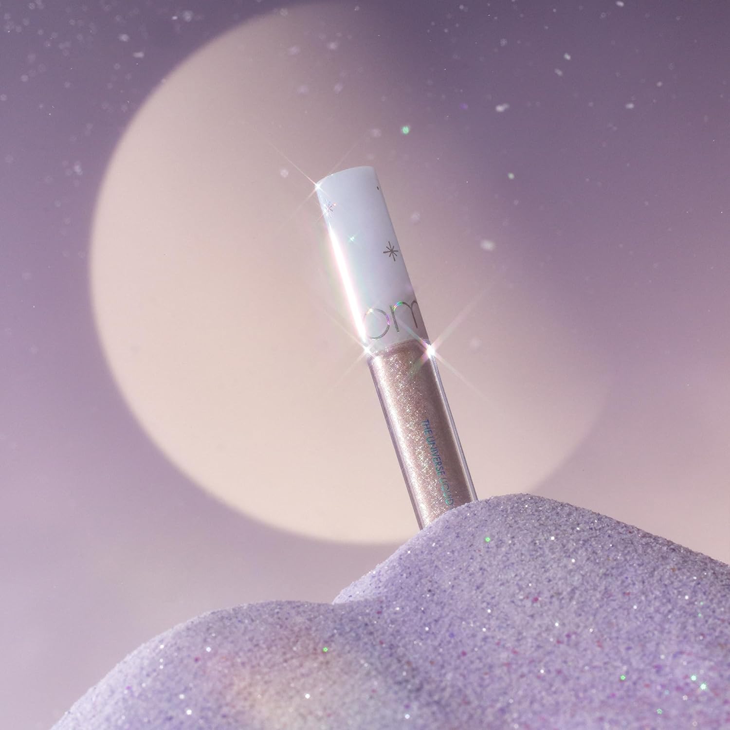 ROMAND The Universe Liquid Glitter, tube pailleté sur fond violet étoilé, éclat holographique de la marque ROMAND.
