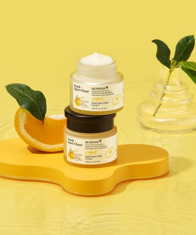 SKINFOOD Yuja C Dark Spot Clear Cream 70ml de SKINFOOD, pot de crème sur fond jaune avec feuilles et agrumes.