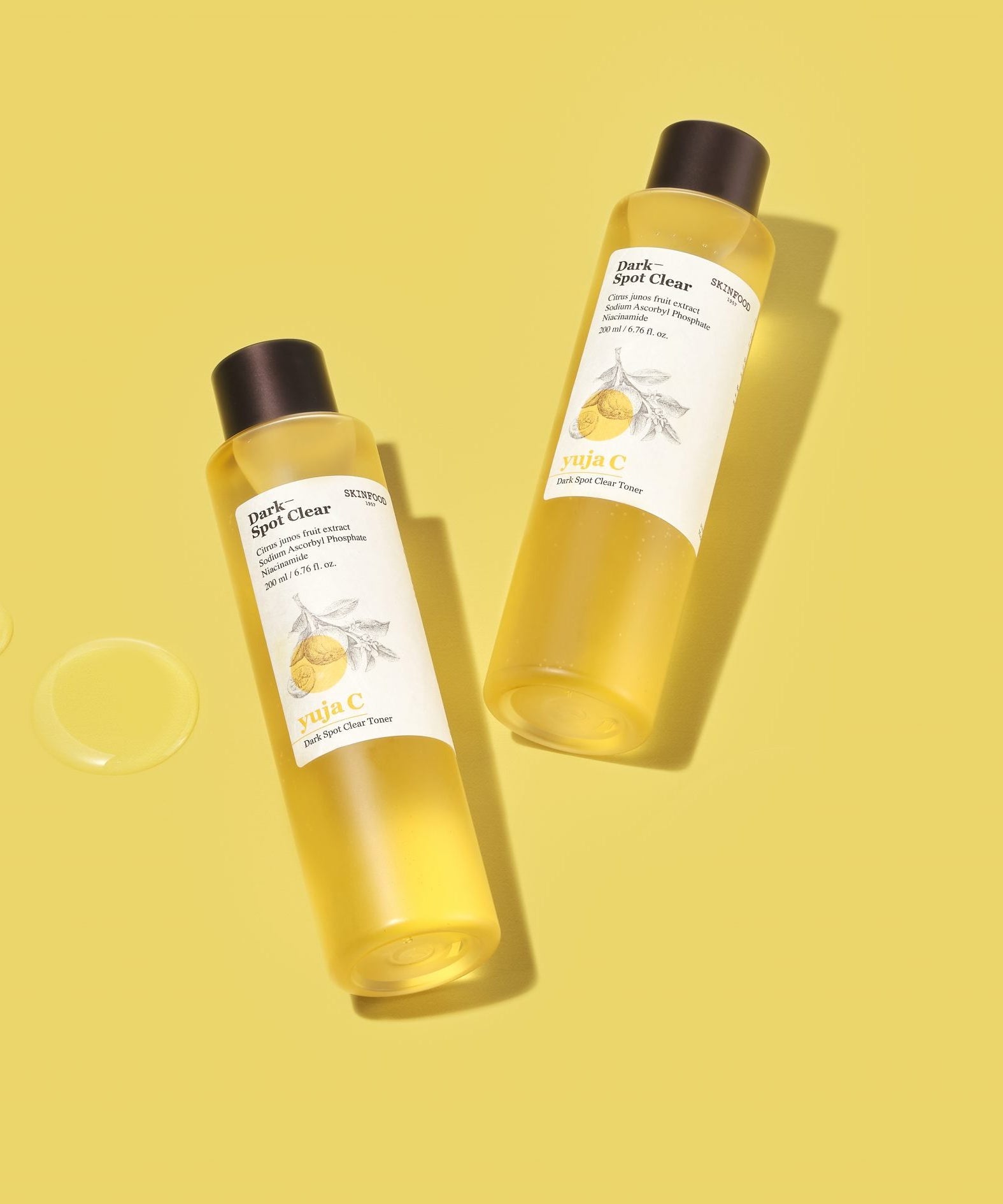 SKINFOOD Yuja C Dark Spot Clear Toner 200ml, flacons sur fond jaune, marque SKINFOOD en contexte beauté