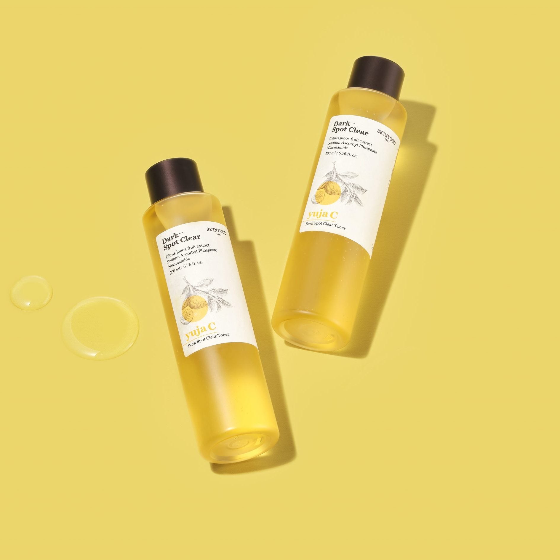 SKINFOOD Yuja C Dark Spot Clear Toner 200ml, flacons sur fond jaune, marque SKINFOOD en contexte beauté