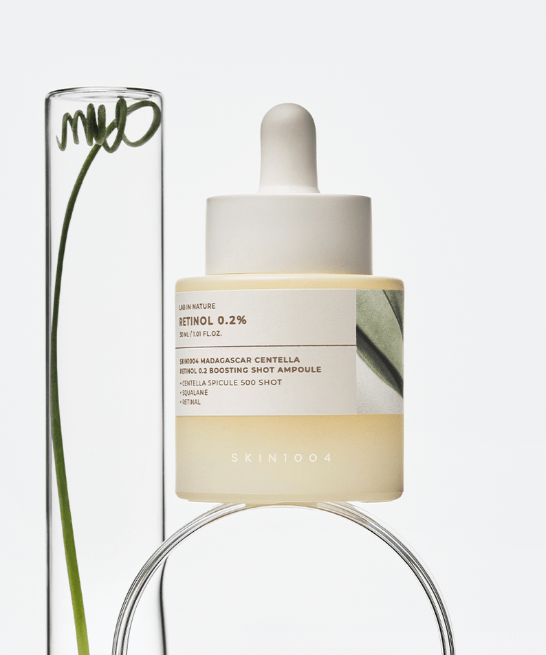 Flacon de SKIN1004 Madagascar Centella Retinol 0.2 Boosting Shot Ampoule 30ml avec plante verte élégante.