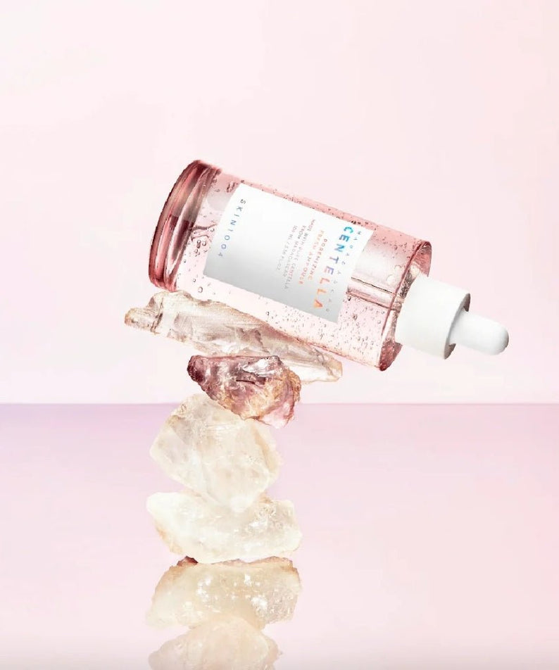 Flacon de SKIN1004 Madagascar Centella Pore-Mfying Fresh Ampoule 100ml sur fond rose pâle, posé sur des cristaux.