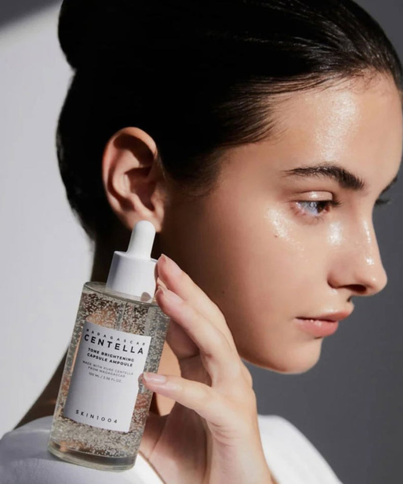Femme tenant SKIN1004 Madagascar Centella Tone Brightening Capsule Ampoule 100ml pour une peau lumineuse et éclatante.