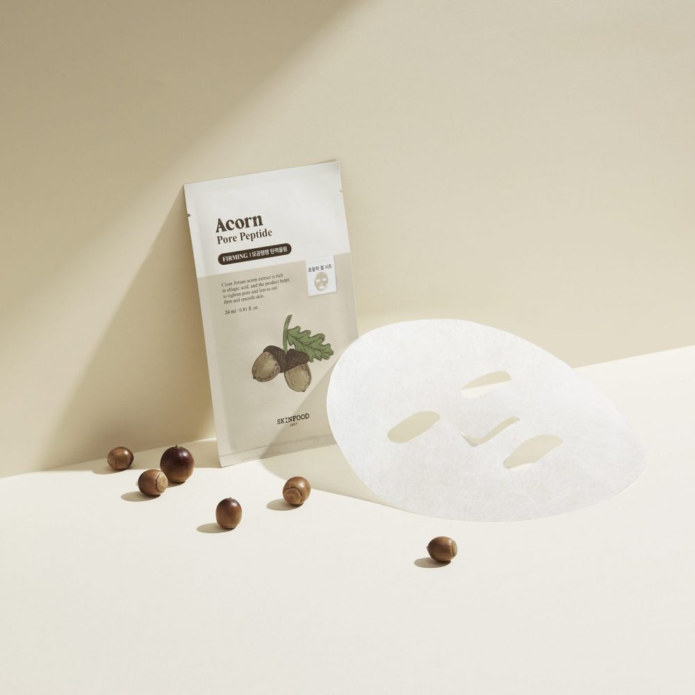 SKINFOOD Acorn Pore Peptide Firming Mask, masque facial en tissu, packaging SKINFOOD sur fond clair avec noisettes