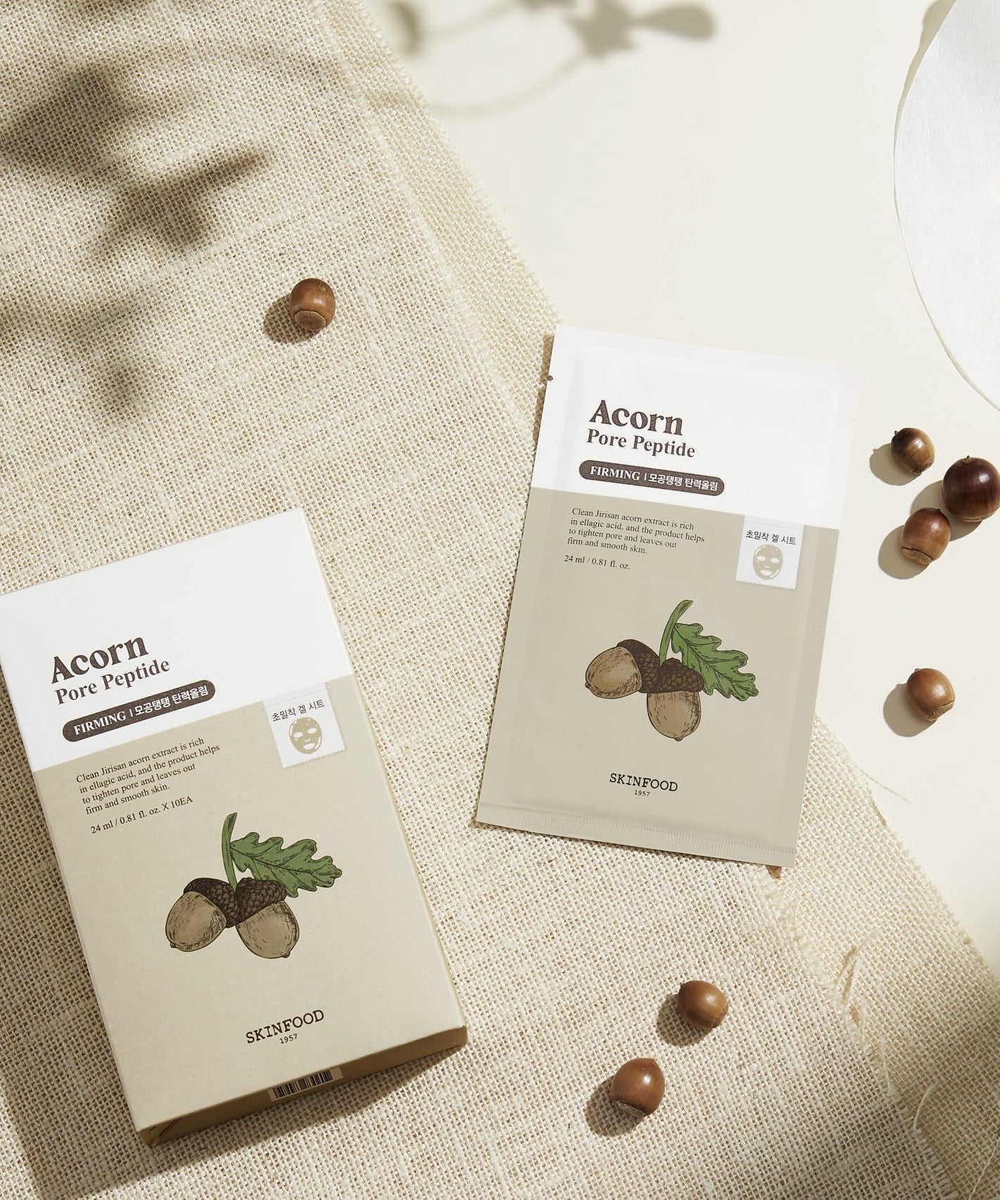 SKINFOOD Acorn Pore Peptide Firming Mask, pack sur tissu beige avec noisettes et feuilles, contexte skincare.