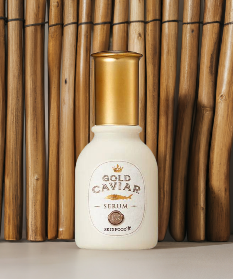 SKINFOOD Gold Caviar EX Serum 50ml, flacon blanc et or devant des bambous, contexte visuel skincare premium.