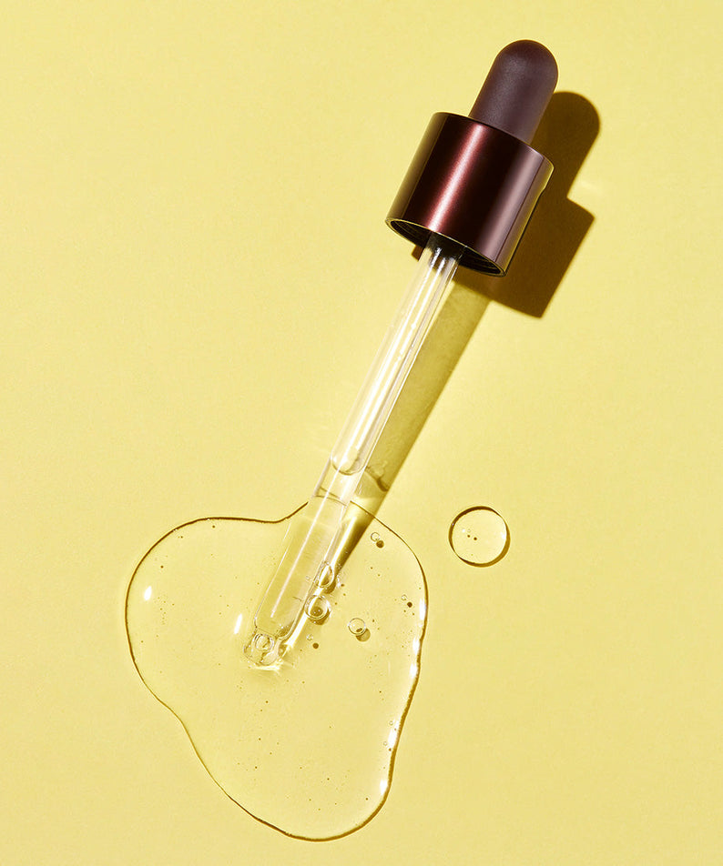 SKINFOOD Yuja C Dark Spot Clear Serum 50ml, flacon sérum sur fond jaune, goutte de vitamine C, lumière studio.