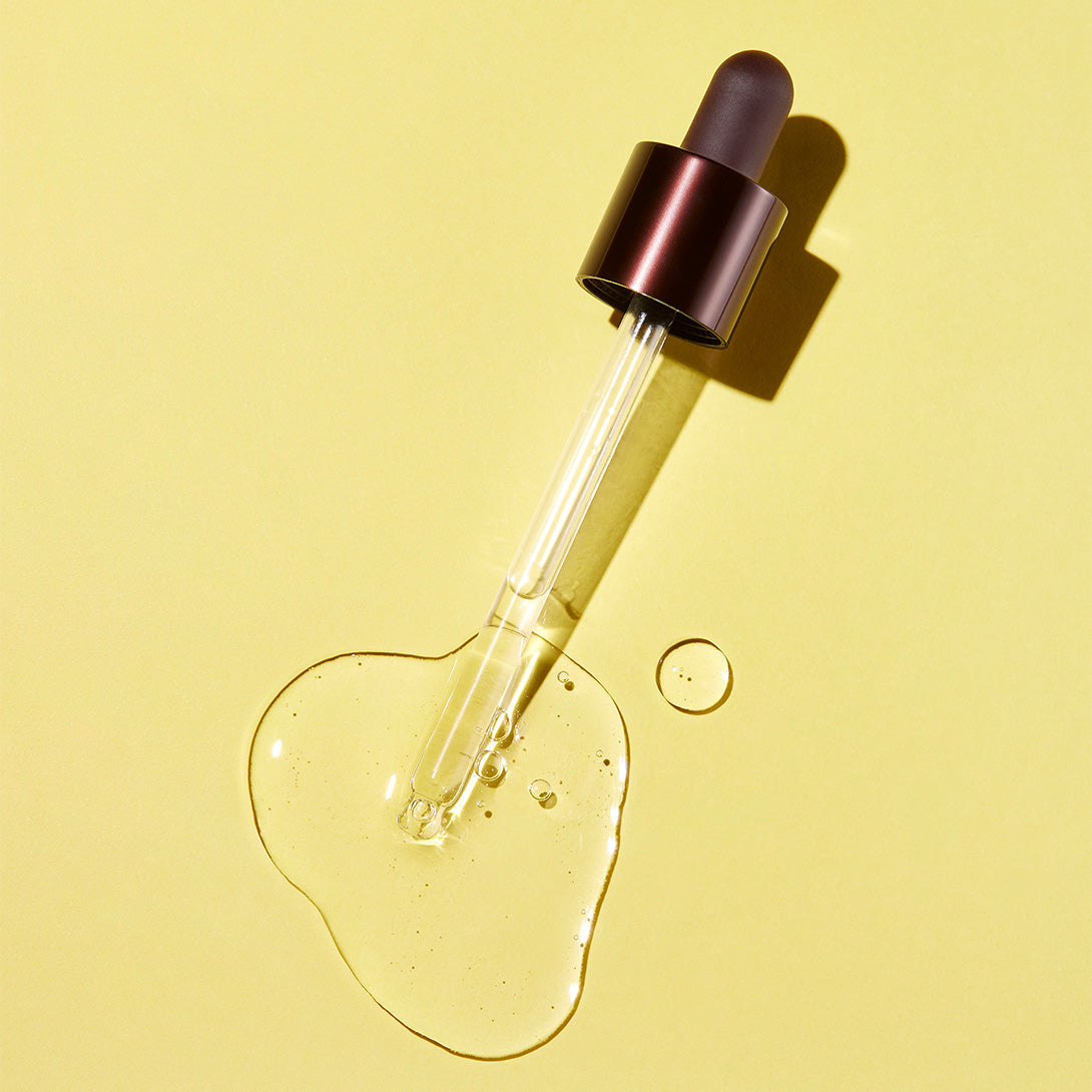 SKINFOOD Yuja C Dark Spot Clear Serum 50ml, flacon sérum sur fond jaune, goutte de vitamine C, lumière studio.